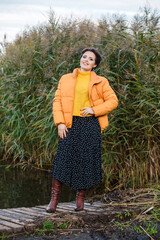 Beautiful young brunette woman posing in a yellow jacket, long skirt and boots. Autumn weather © ribalka yuli