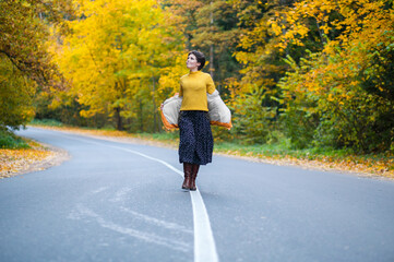 Full-length photo of young woman on  road in autumn forest,  walking in fresh air, enjoying freedom and solitude. Happy people