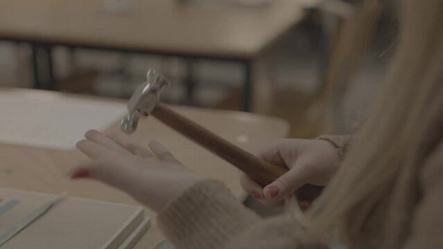 Woman picking up woodwork hammer, hammering, workshop tools