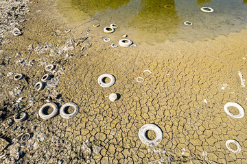 Old tire illegally abandoned in Po river visible due to drought. Carmagnola, Italy - July 2022