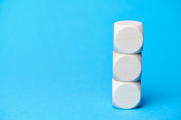 three wooden cubes on each other, copy space for any text, blue background paper