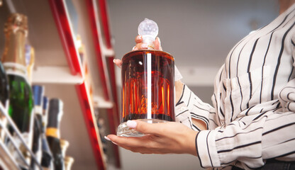 Woman buying cognac at supermarket.
