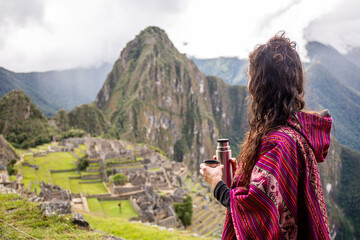 Fototapeta na wymiar Woman Looking at Inca Citadel called Machupichu built of stones on the mountain, cloudy day, Peru