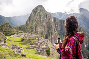 Fototapeta na wymiar Woman Looking at Inca Citadel called Machupichu built of stones on the mountain, cloudy day, Peru