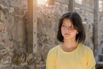 Fototapeta na wymiar Portrait of a young girl posing against a stone wall.
