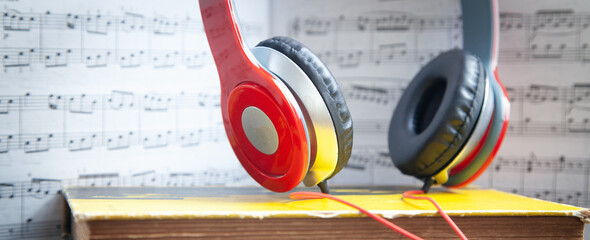 Headphones and book on music note.