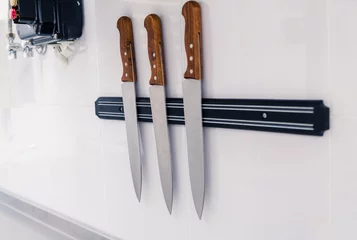 Fotobehang Set of knives on magnetic holder  on white wall © ribalka yuli