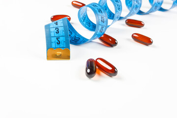Pile of leptin capsules with blue measuring tape on white background. Concept of losing weight,...