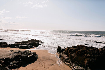 Photo of ocean waves with stone beach in sunlight. Exotic landscape with blue sky and spring ocean 