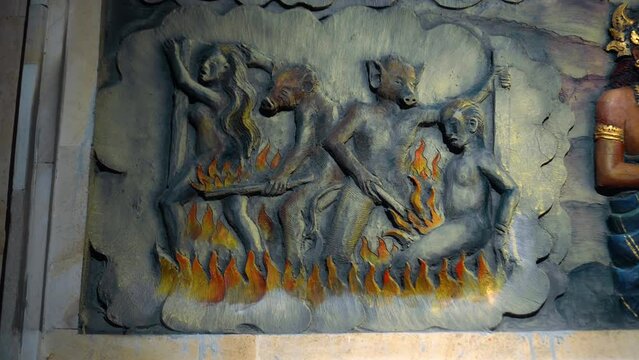 A painting on a wall in a Buddhist temple depicting hell. Torment of sinners. Servants of hell burn souls with fire in hell.
