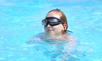 A girl with glasses swims in the pool.