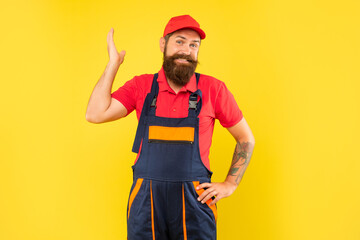 smiling funny bearded man technician in work clothes on yellow background