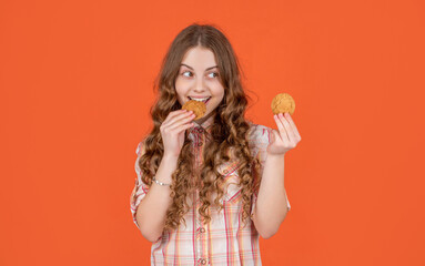 happy teen kid eating oatmeal cookies on orange background