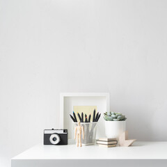Creative desk with notebook, desk objects, office supplies, books on a bright background.	
