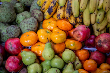 different organic fruits put in a market, custard apple, banana, pear, pomegranate and tangerines