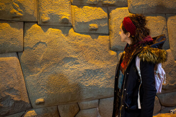 Tourist woman looking at the stone of the 12 angles at night in Cusco, Peru