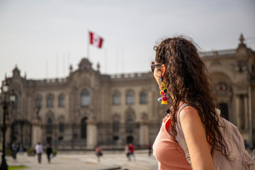 Tourist woman looking at the Government Palace of Peru, Plaza Mayor of Lima. on cloudy day