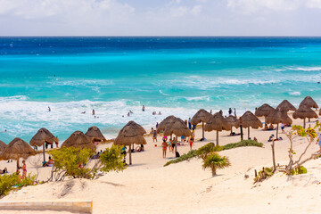 Umbrelas on a sandy beach with azure water on a sunny day near Cancun, Mexico