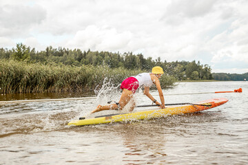 Paddling on a SUP board on a lake at sunny day. Stand up paddle boarding - awesome active outdoor recreation.