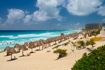 Umbrelas on a sandy beach with azure water on a sunny day near Cancun, Mexico