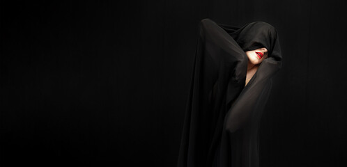 red made up mouth of female beauty model covered with black fabric on black background, wide banner...