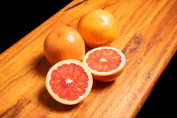 Grapefruit, several grapefruits and one cut in half on a rustic wooden surface, selective focus.