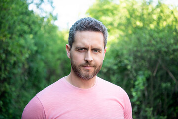Portrait of handsome unshaven guy natural background outdoors