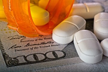 Close-up of pharmaceutical cost concept with  100 dollar bill pill bottle and pills