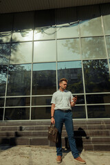 A young businessman man with a mobile phone near a glass building