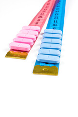 Pills with pink and blue measuring tape on white background. Concept of losing weight, diet, fat burning, healthy eating. Copy space.