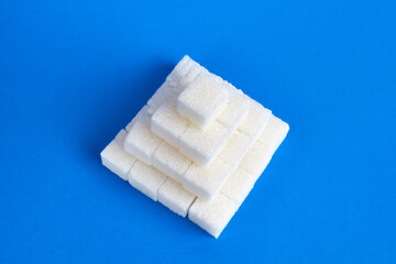Cubes of pressed sugar stacked in a pyramid on a blue background.