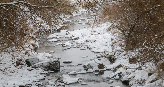 Rocky Creek In The Snow Surrounded By Brown Brush