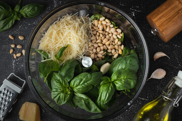 Ingredients for pesto sauce in the blender bowl. Green basil leaves, Parmesan cheese and pine nuts...