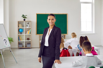 Portrait of beautiful and intelligent female primary school teacher against background of her...