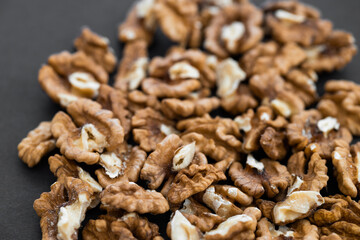 closeup of shelled organic walnut halves on black background