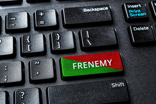 Frenemy word on the green red enter key of a desktop pc keyboard. Laptop computer enter key with warning message. Be an enemy while pretend to be a friend and antagonistic person comcept.