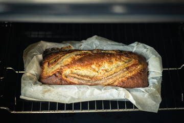 Fresh banana bread getting ready in the oven. Close up of hot homemade pastry in a baking dish with parchment