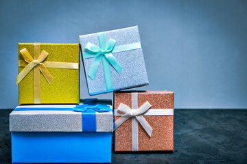 Multi colored gift boxes with bows different colors gray background.