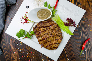 juicy Ribeye steak on plate with pepper sauce on wooden table