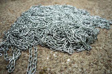 A metal chain on a concrete floor. Silver chain for construction.