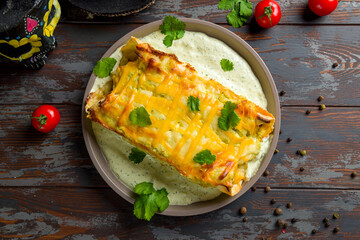 Enchilada with chicken and cheese on plate, mexican kitchen top view