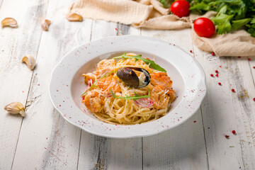 Pasta with seafood on white plate on wooden table