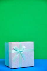 Gift box with turquoise ribbon is tied with bow.
