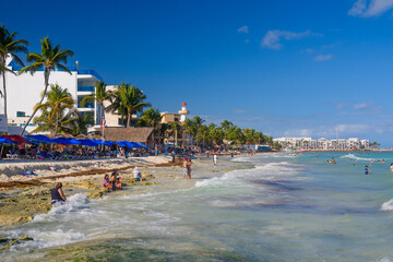 Obraz premium People swimming among splashes and waves on the beach with hotels in Cancun, Yukatan, Mexico
