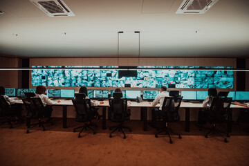 Group of Security data center operators working in a CCTV monitoring room looking on multiple monitors Officers Monitoring Multiple Screens for Suspicious Activities Team working on the System Contr
