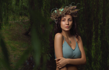 Pretty woman wearing floers laurel wreath in the forest with copy space