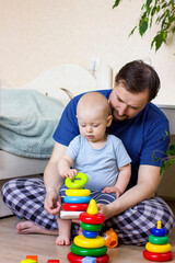 Father and baby boy building a pyramid toy.