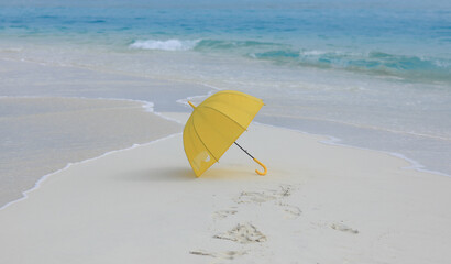 yellow umbrella on the white sand of the ocean