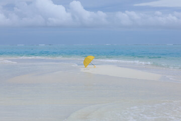 yellow umbrella on the white sand of the ocean