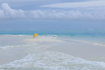 Fototapeta na wymiar yellow umbrella on the white sand of the ocean